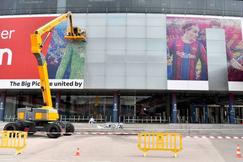Workers remove a poster featuring Barcelona's departing forward Lionel Messi at the Camp Nou stadium.