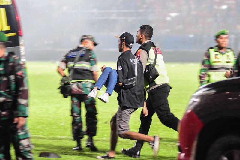 People help carry an injured spectator after a football match between Arema FC and Persebaya on October 1. AFP