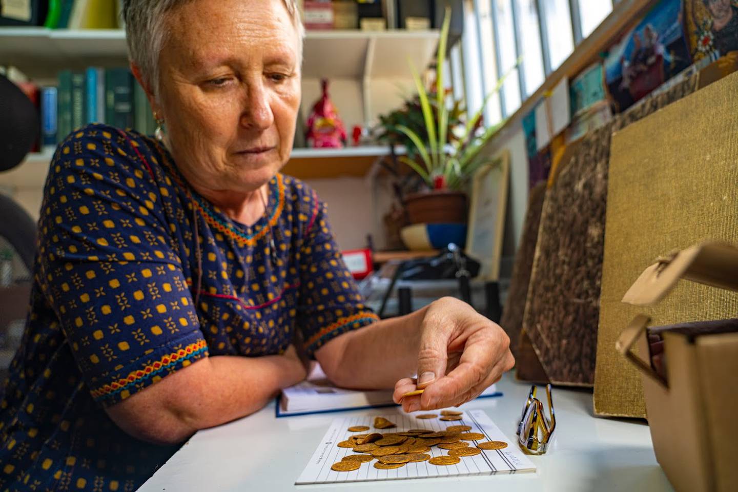 Gabriela Bijovsky, a currency expert at the Israel Antiquities Authority, examines the coins from Banias. Photo: Israel Antiquities Authority