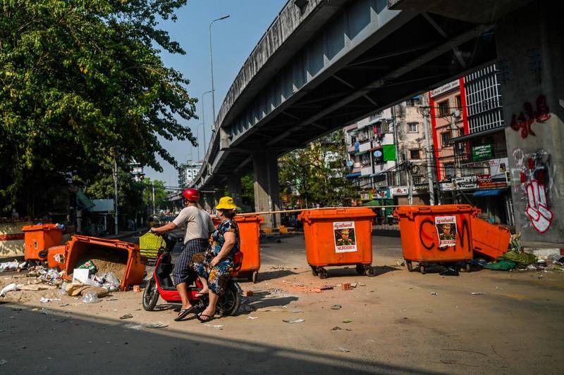 A scooter rider attempts to ride past a makeshift barricade of wheelie bins, with the image of Myanmar armed forces chief Gen Min Aung Hlaing stuck on them, during demonstrations against the military coup, in Yangon, Myanmar. AFP
