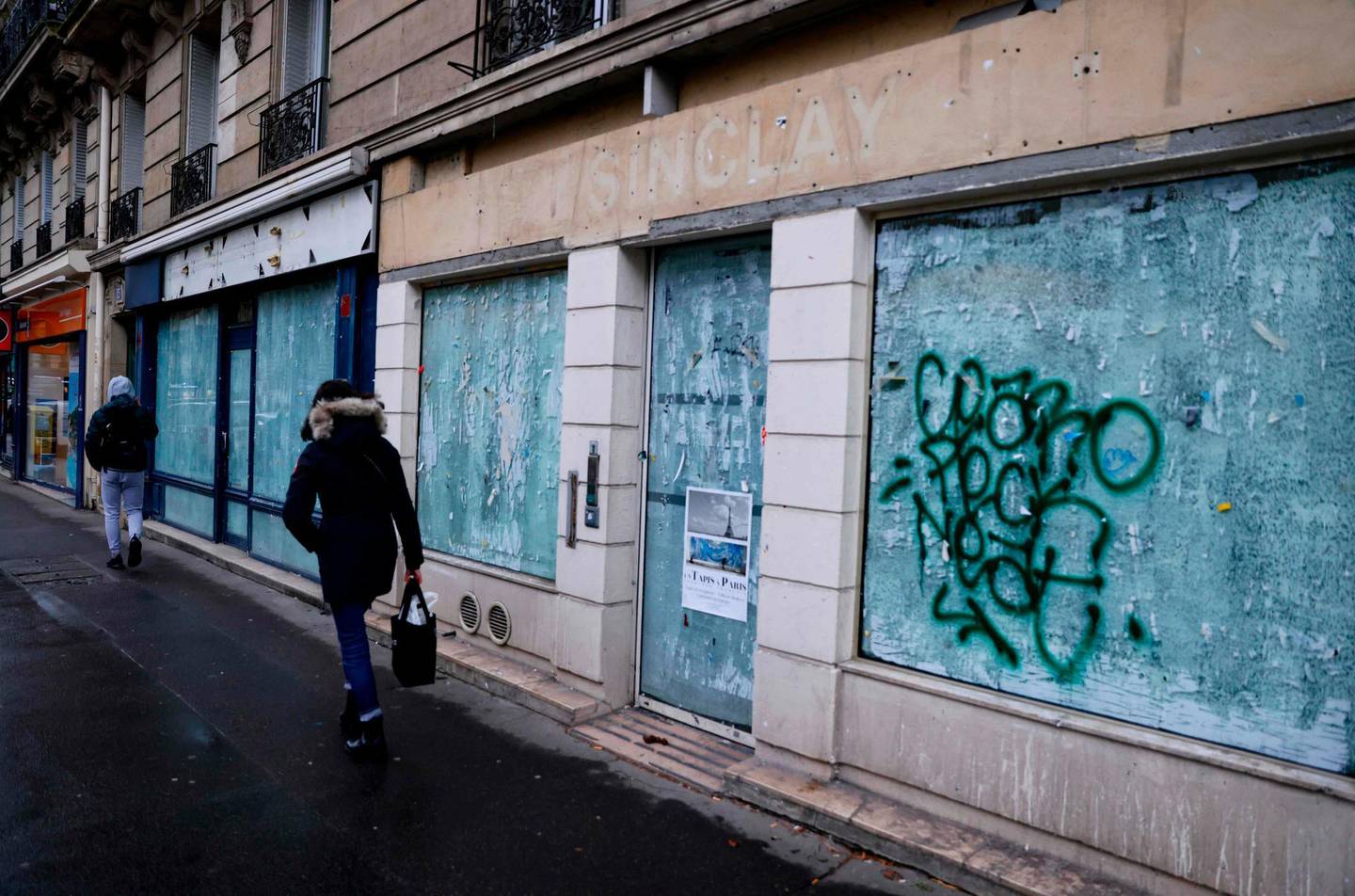 Pedestrians walk past closed shops in Paris on January 5, 2021. / AFP / THOMAS SAMSON
