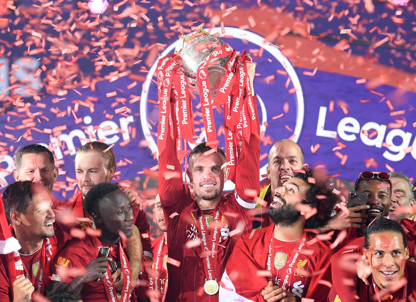LIVERPOOL, ENGLAND - JULY 22: Jordan Henderson of Liverpool holds the Premier League Trophy aloft along side Mohamed Salah as they celebrate winning the League during the presentation ceremony of  the Premier League match between Liverpool FC and Chelsea FC at Anfield on July 22, 2020 in Liverpool, England. Football Stadiums around Europe remain empty due to the Coronavirus Pandemic as Government social distancing laws prohibit fans inside venues resulting in games being played behind closed doors. (Photo by Laurence Griffiths/Getty Images)