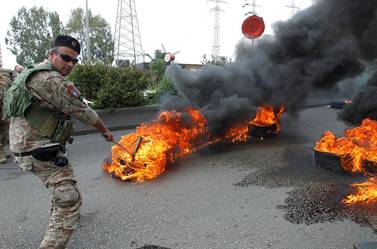 A Lebanese soldier tries to open a highway blocked by the burning tires, during a protest against the collapsing Lebanese pound currency and the price hikes in Zouk, north of Beirut. Reuters