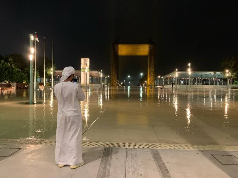 An Emirati takes a photo of a wet Expo City Dubai on Saturday night. Chris Whiteoak / The National