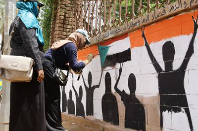 Young Sudanese women paint a wall.  EPA
