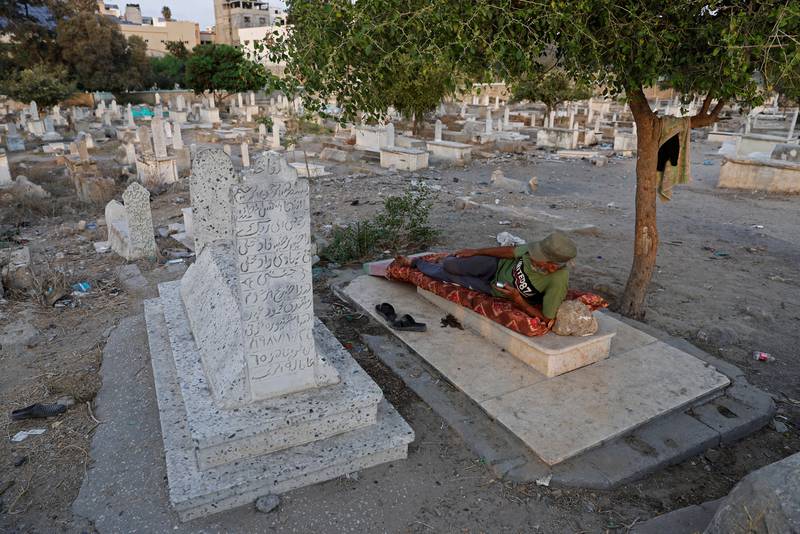 Omar Kuhail, 65, rests on a grave in Sheikh Shaban cemetery. Homeless squatters live in Gaza's cemeteries while authorities grapple with demand for new housing.