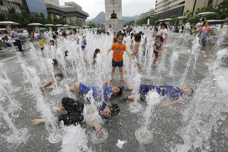 Children cool off in a fountain in Seoul. Ahn Young-joon / AP Photo