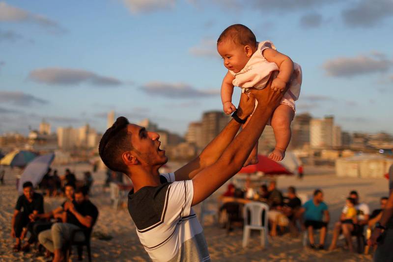 A Palestinian man lifts up a baby on the beach in Gaza City after coronavirus restrictions in the territory were largely eased. Reuters