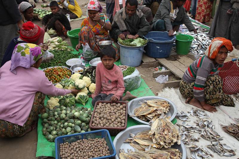 A child looks on as Rohingya vendors sell vegetables at a market at Thet Kal Pyin camp in Rakhine Sate. AFP