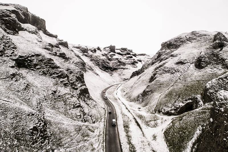 Cars drive along Winnats Pass as snow and ice swept across parts of Britain, near Castleton, in the Peak District, England, Tuesday Dec.  13, 2022.  (Danny Lawson / PA via AP)
