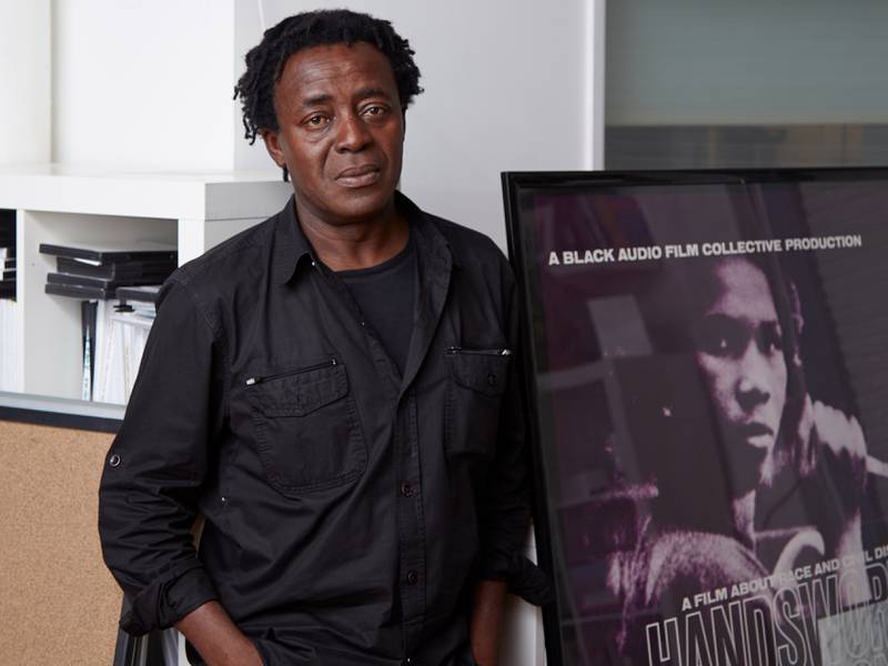 John Akomfrah in his London studio with a poster for the film Handsworth Songs, made with the Black Audio Film Collective. Photo: British Council