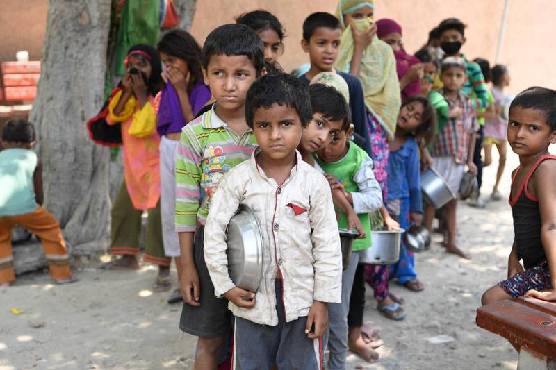 Children from a slum stand in queue to get free food after the government eased a  nationwide lockdown as a preventive measure against the COVID-19 coronavirus, in New Delhi on June 15, 2020. (Photo by Prakash SINGH / AFP)