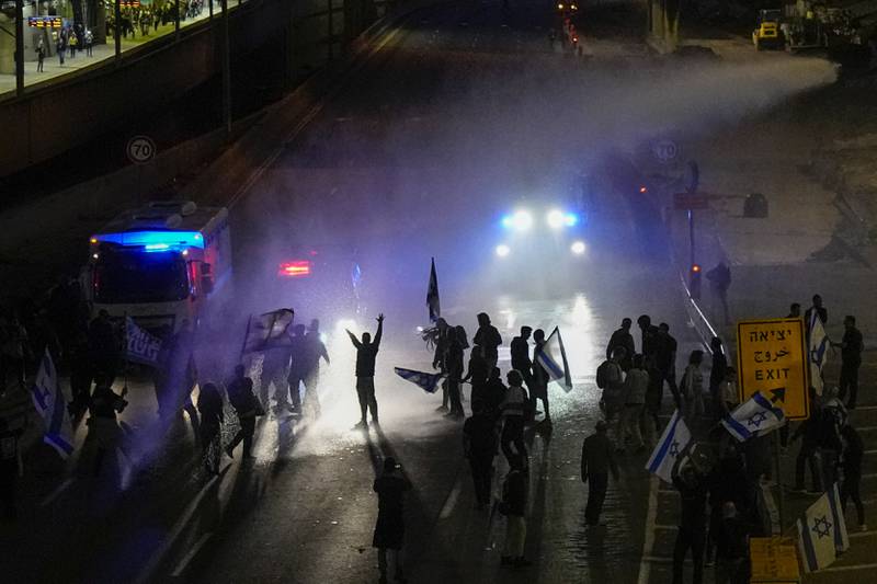 Police use a water cannon to disperse protesters. AP