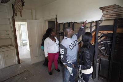 People look at a missing section of a wall as they tour a home being auctioned off in Boston-Edison. The city of Detroit says nearly 6,000 people have already registered on the auction website to bid on homes. Joshua Lott / Reuters