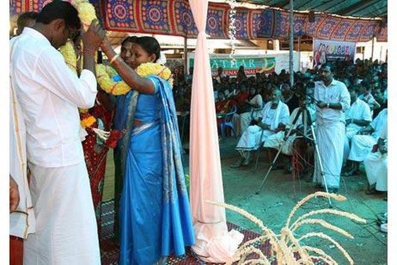 The bride, Usha, garlands the groom, Unni Krishnan, during the mass wedding organised in Changaramkulam, Kerala. Nine couples were wed in ceremonies on Sunday sponsored by an Abu Dhabi social group.