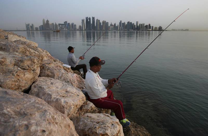 In this May 4, 2018 photo, people fish in the early morning with the skyline in the background, in Doha, Qatar. Saudi Arabia, Egypt, the United Arab Emirates and Bahrain severed diplomatic ties and cut air, ground and sea links to Qatar over its alleged support of terrorist groups and its warm relations with Iran. But Qatarâ€™s massive natural gas reserves and close ties with other countries in the region have allowed it to weather the crisis, and daily life has gone on largely unchanged. (AP Photo/Kamran Jebreili)