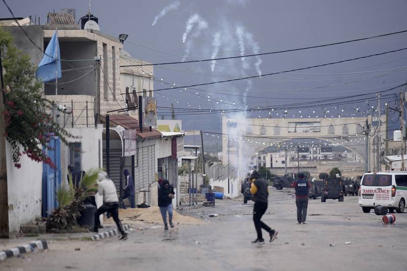 Palestinians run from teargas fired by Israeli forces during a raid on the Aqabat Jabr camp near Jericho in the occupied West Bank. AP