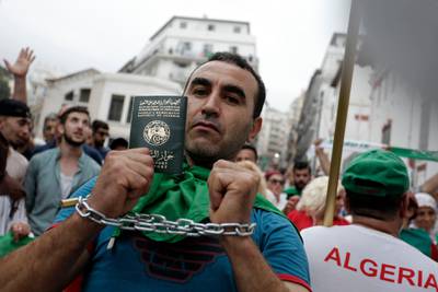 A man who symbolically chained his arms shows his passport during a demonstration in Algiers. Thousands of pro-democracy protesters took to the streets of the capital on Friday, chanting defiantly in the face of a crackdown on the demonstration by the country's powerful army chief. AP Photo