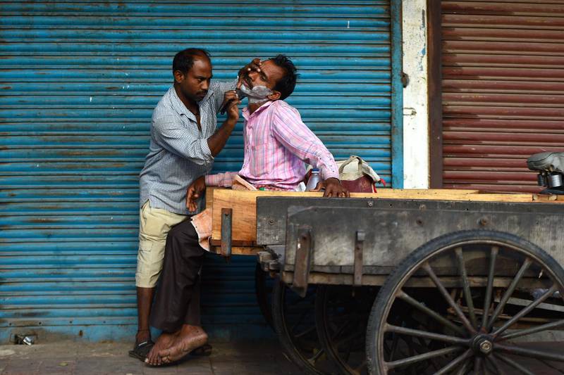 A man gets a shave outside closed shops during a government-imposed nationwide lockdown as a preventative measure against the COVID-19 novel coronavirus in the old quarters of New Delhi.  AFP