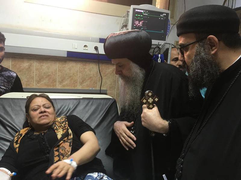 Egypt's Coptic priest Agathon, centre, speaks to a woman who was wounded after gunmen attacked a bus. AFP