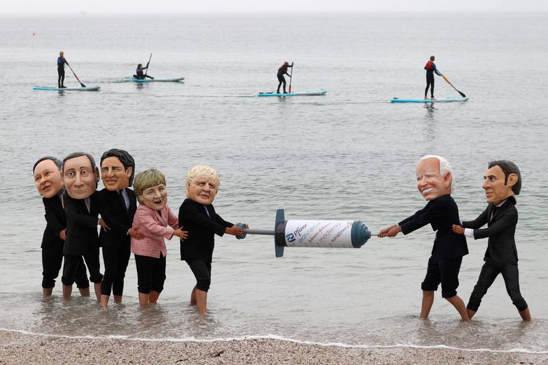 Activists wearing giant heads of the G7 leaders tussle over a Covid-19 vaccine syringe during an action by charity Oxfam to highlight intellectual property for vaccines, on Swanpool beach, Cornwall, on the sidelines of the G7 summit. AFP