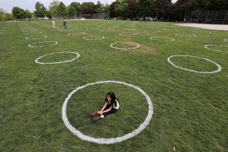 A girl sits in a field where circles were painted to help visitors maintain social distancing at Trinity Bellwoods park in Toronto, Ontario, Canada. Reuters