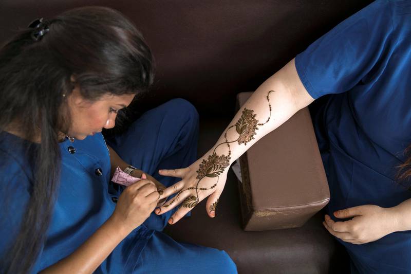 ABU DHABI, UNITED ARAB EMIRATES - AUGUST 16, 2018. Chathurika Samanmali, 25, puts henna on Mafia Shabbir, 28, her colleague, at Abeer Beauty & Henna salon in Baniyas.(Photo by Reem Mohammed/The National)Reporter: Anna ZachariasSection:  NA
