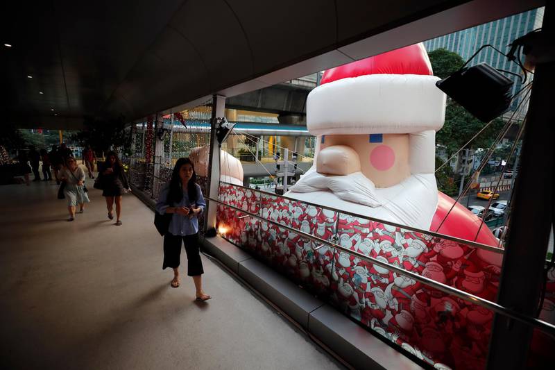 People walk past a large inflatable Santa Claus outside a shopping mall in Bangkok, Thailand. EPA