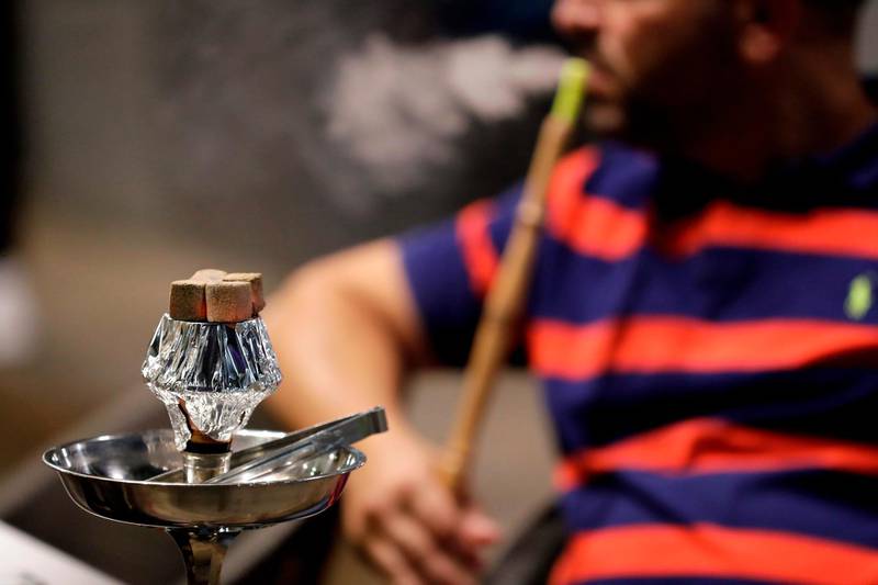 A Lebanese man smokes a waterpipe at a restaurant in the coastal city of Batroun north of Beirut on May 22, 2019.  Lebanese government who has been debating the cuts on the budget for weeks, have decided to impose a 1,000 Lebanese pound tax ($0.66) on every waterpipe consumed in a restaurant or hotel. / AFP / JOSEPH EID

