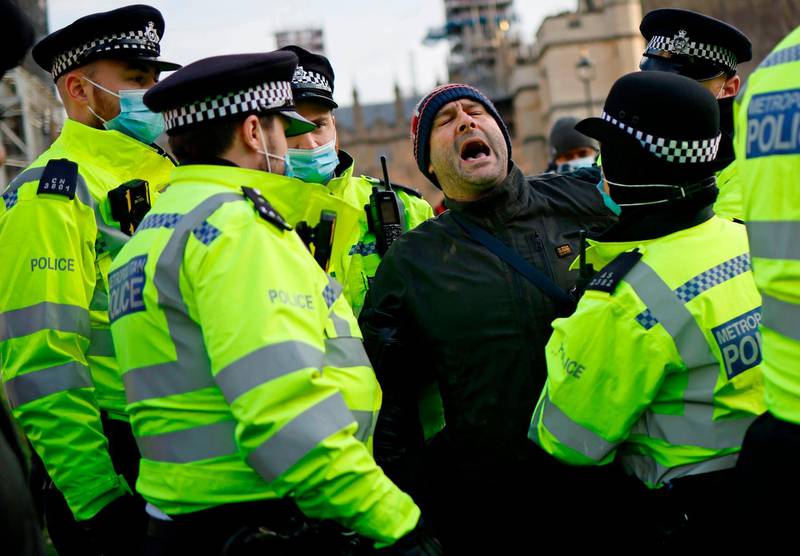 Police officers detain a protestor during an anti-lockdown demonstration outside the Houses of Parliament in Westminster, central London. AFP