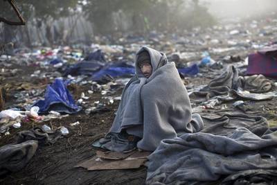 A man stays warm by wrapping himself in a blanket as he waits to cross Serbia's border with Croatia in Berkasovo on October 24, 2015. Marko Drobnjakovic/AP Photo