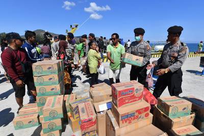 Indonesian police and volunteers unload supplies and aid.  AFP Photo