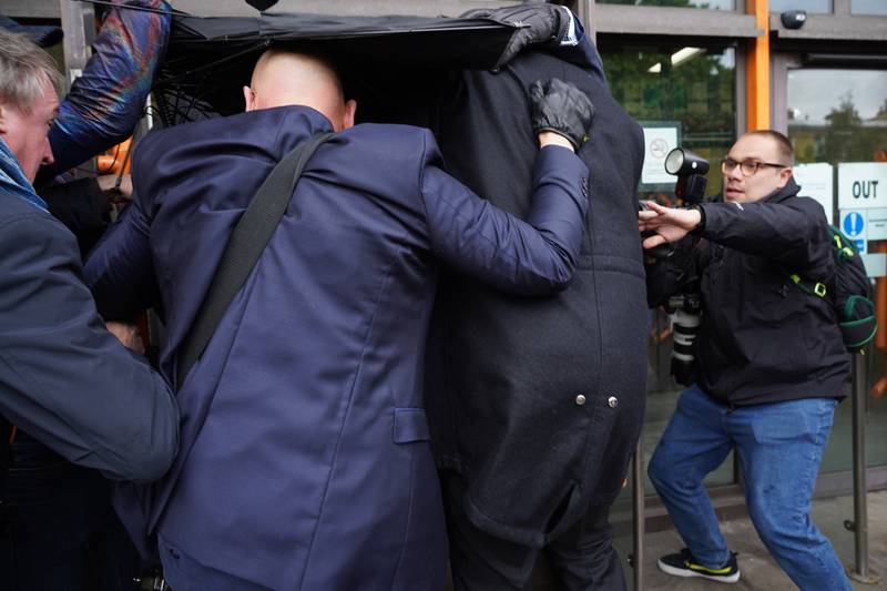 West Ham United defender Kurt Zouma is hidden from photographers underneath umbrellas as he arrives in court. PA