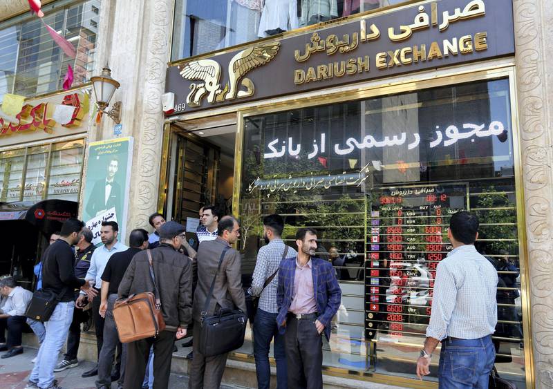 Iranians walk past a currency exchange shop in the capital Tehran on April 10, 2018.
Iran took the drastic step of fixing the rate of its currency against the dollar in a bid to arrest a slide that has seen it fall by a third in six months. / AFP PHOTO / ATTA KENARE