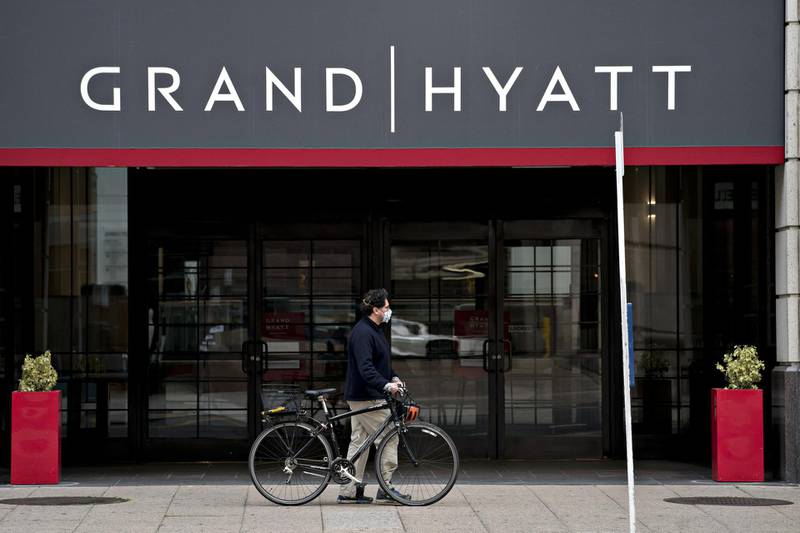 A pedestrian wearing a protective mask walks a bicycle past the Grand Hyatt hotel in Washington, D.C., U.S., on Thursday, April 23, 2020. The largest U.S. hotel and lodging chains including Hyatt Hotels Corp. have raised more than $21 billion in loans since March 9 to help weather the coronavirus storm. Photographer: Andrew Harrer/Bloomberg