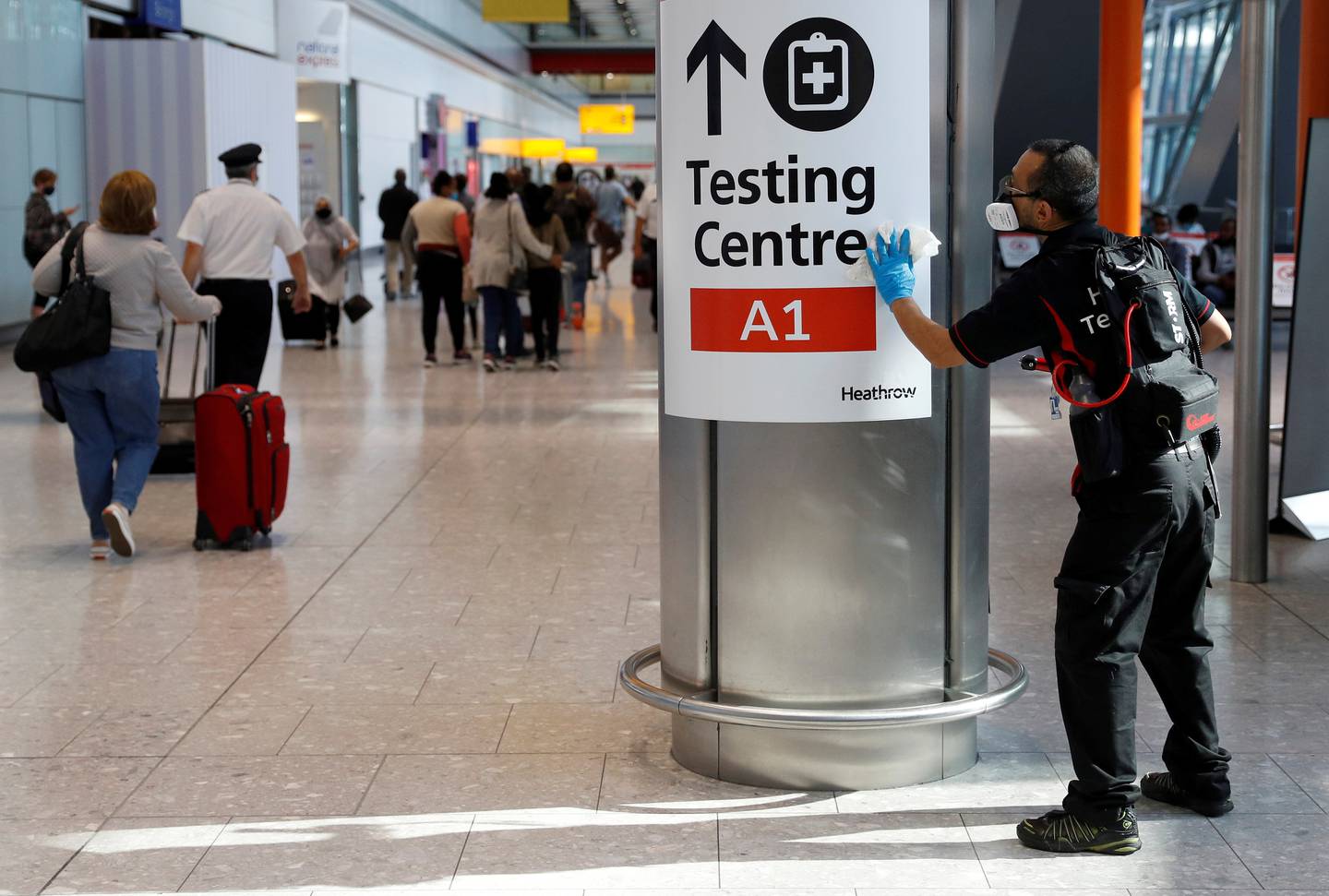 A member of staff sanitises sign boards at Terminal 5 in London's Heathrow Airport. Reuters