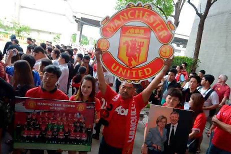 Manchester United football fans hold posters as the team in Thailand.