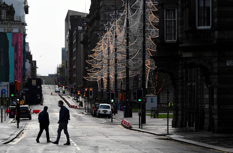 Pedestrians cross a near-deserted George Street in central Glasgow. AFP