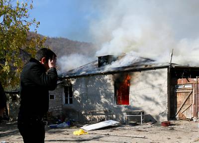 A man reacts as he stands near a house set on fire by departing Ethnic Armenians, in an area which is soon to be turned over to Azerbaijan, in the village of Cherektar.  Reuters