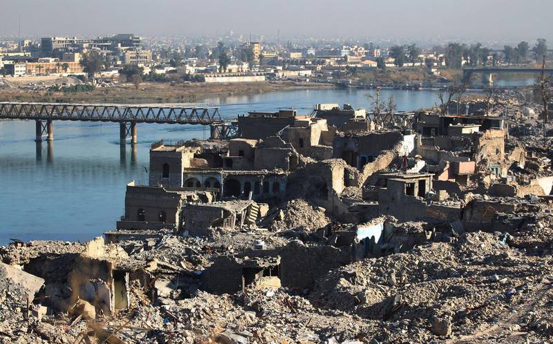 A picture shows the destruction of the old city of Mosul with the city's old bridge over the Tigris river in the background, on January 9, 2018.
Along the waterfront of the Tigris River in Iraq's war-torn Mosul, gaping holes in hotel walls reveal little but enormous heaps of rubble. Six months since Iraqi forces seized the country's second city from Islamic State group jihadists, human remains still rot in front of the Al-Nuri mosque. / AFP PHOTO / AHMAD AL-RUBAYE