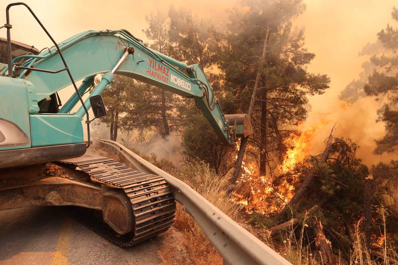 A digger helps to extinguish a forest fire in Datca, on Turkey's Aegean coast. AFP