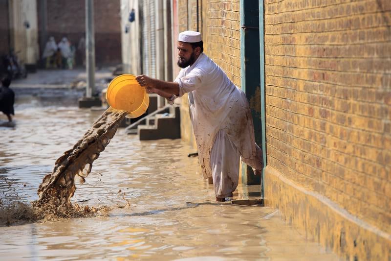 A man throws water out of his flooded home in Nowshera. EPA