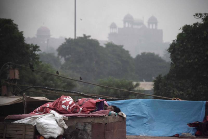 Indian woman sleeps in front of the Red Fort as smog envelop the old quarters of New Delhi on November 6, 2017. / AFP PHOTO / DOMINIQUE FAGET