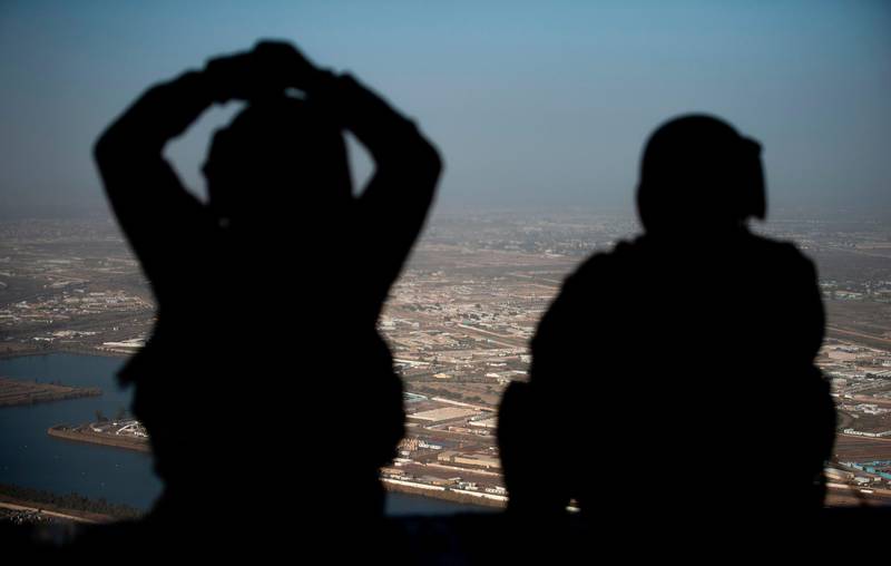 (FILES) In this file photo US Army helicopter crew members look out of their Chinook helicopter as they fly from the US Embassy to Baghdad International airport, following the helicopter of US secretary of State Mike Pompeo, over the Iraqi capital Baghdad on January 9, 2019.  Secretary of State Mike Pompeo warned Iraq on March 16, 2020 the US would retaliate "as necessary" against any new assaults on Americans after a slew of rocket attacks.The United States last week launched airstrikes against an Iranian-allied paramilitary group following a deadly attack on an Iraqi base housing US troops -- but rocket fire has continued unabated.
 / AFP / POOL / ANDREW CABALLERO-REYNOLDS
