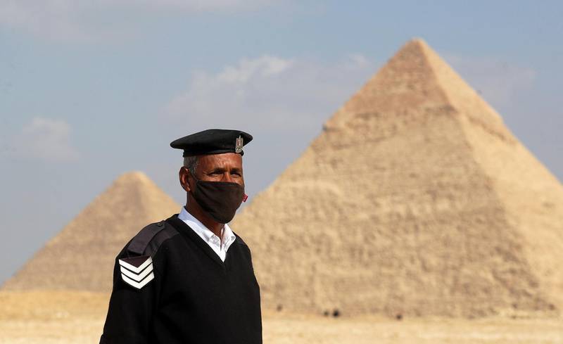 A police officer wearing a protective face mask stands guard in front of the Great Pyramids of Giza in Giza, Egypt December 18, 2020. REUTERS/Mohamed Abd El Ghany