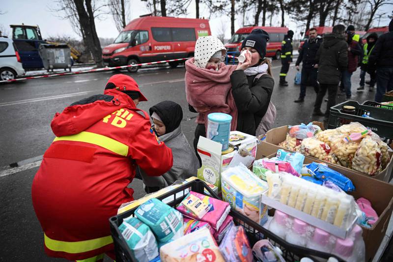 A Romanian emergency services worker puts a blanket on a child. AFP