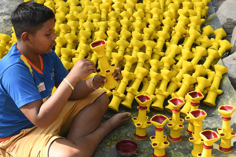 A craftsman paints earthen lamps in Amritsar. AFP