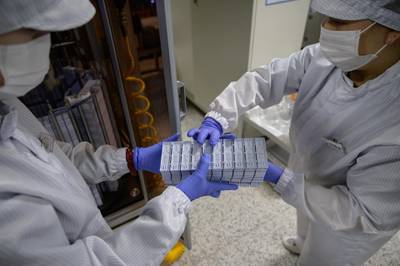 Staff members restock a machine with components used in testing for Covid-19 novel coronavirus. AFP