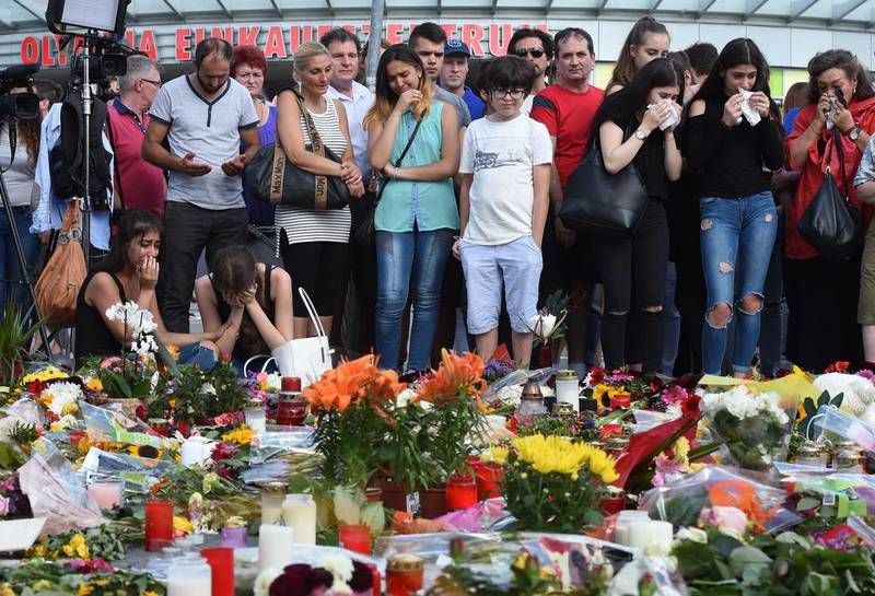 People mourn in front of candles and flowers at the site of a Munich shopping centre where an 18-year-old German-Iranian student killed nine people. Christof Stache / AFP

