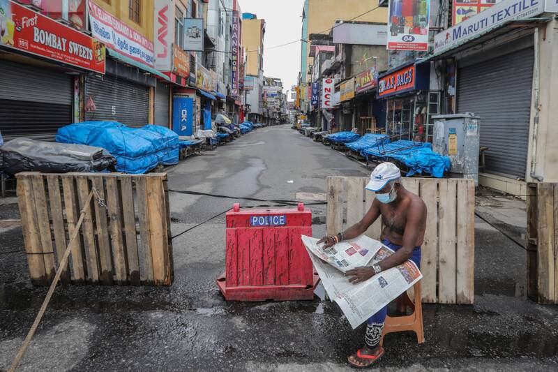 A man reads a newspaper next to closed shops after the government announced an island-wide lockdown in Colombo, Sri Lanka. EPA